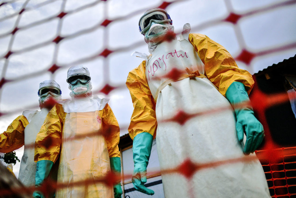 Workers stand over an Ebola victim