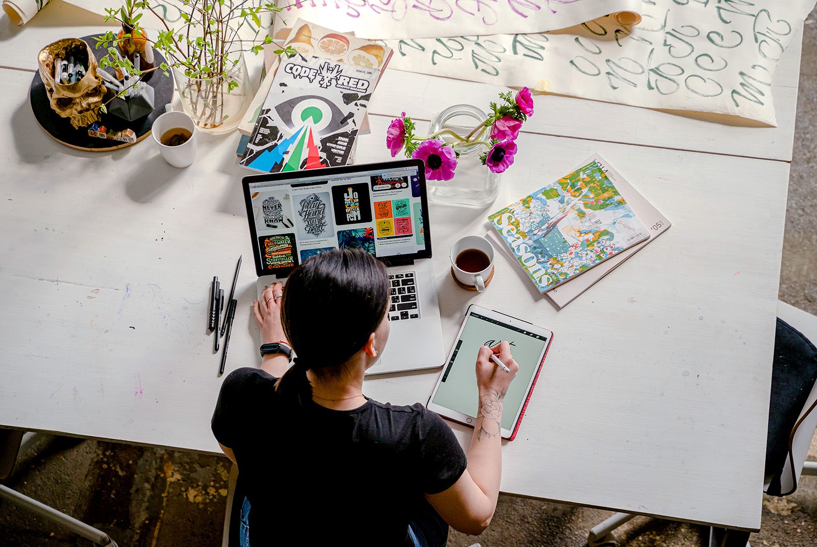 Woman writing on tablet computer while using laptop.