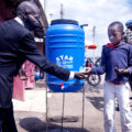 A child helps an adult wash his hands.