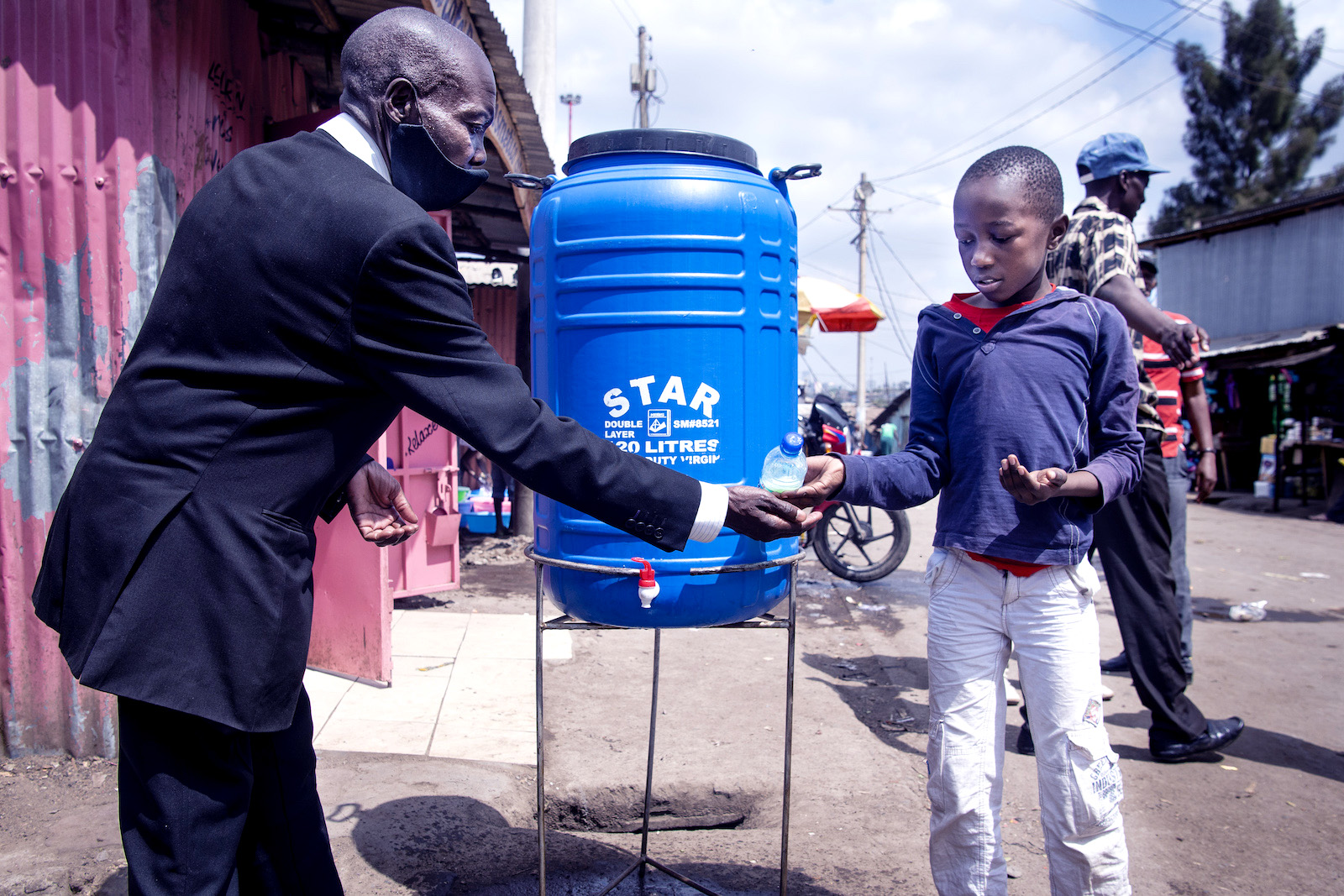 A child helps an adult wash his hands.