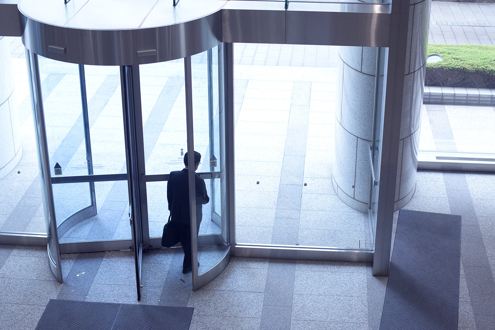 Businessman leaving the revolving door of the office building.