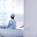 Senior African-American woman sitting on bed, thinking