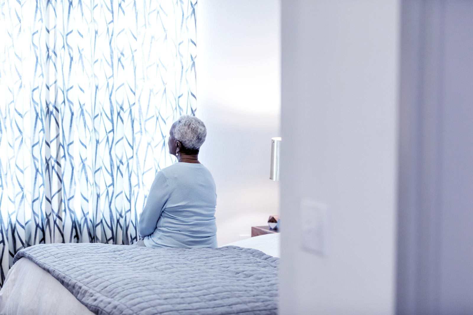 Senior African-American woman sitting on bed, thinking