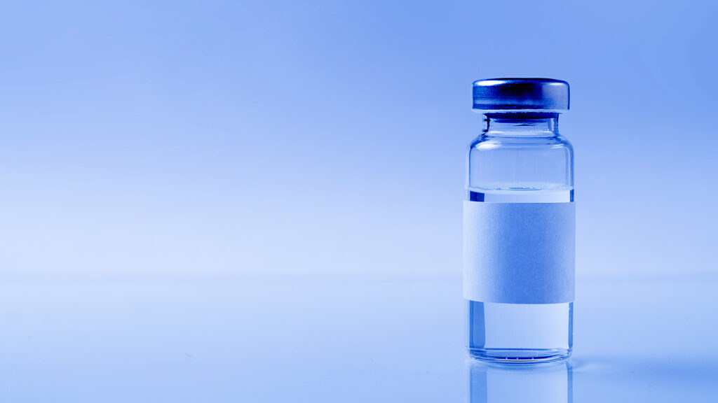 a glass medical bottle or ampoule with a vaccine for covid-19 or for colds and flu on a white background. The concept of treatment and prevention of the spread of infection, virus and pneumonia.