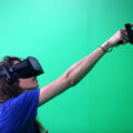 A woman wearing a VR headset points while in virtual reality
