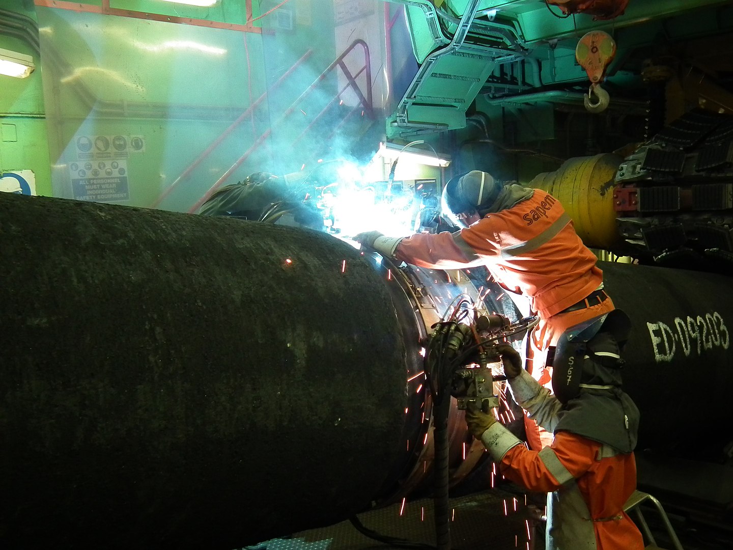 A photo of a worker welding two pipes together