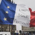 A French flag bearing the words liberté, egalité, fraternité waves in the wind