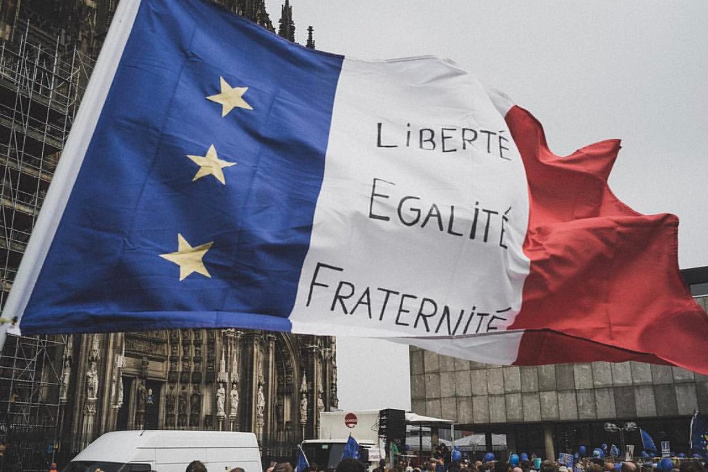 A French flag bearing the words liberté, egalité, fraternité waves in the wind