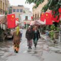 Photo of three women walking down a street under Chinese flags in Kashgar, Xinjiang, China