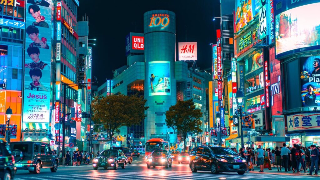 A photo of city square at night with neon signs for shops in Shibuya, Japan
