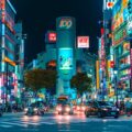 A photo of city square at night with neon signs for shops in Shibuya, Japan