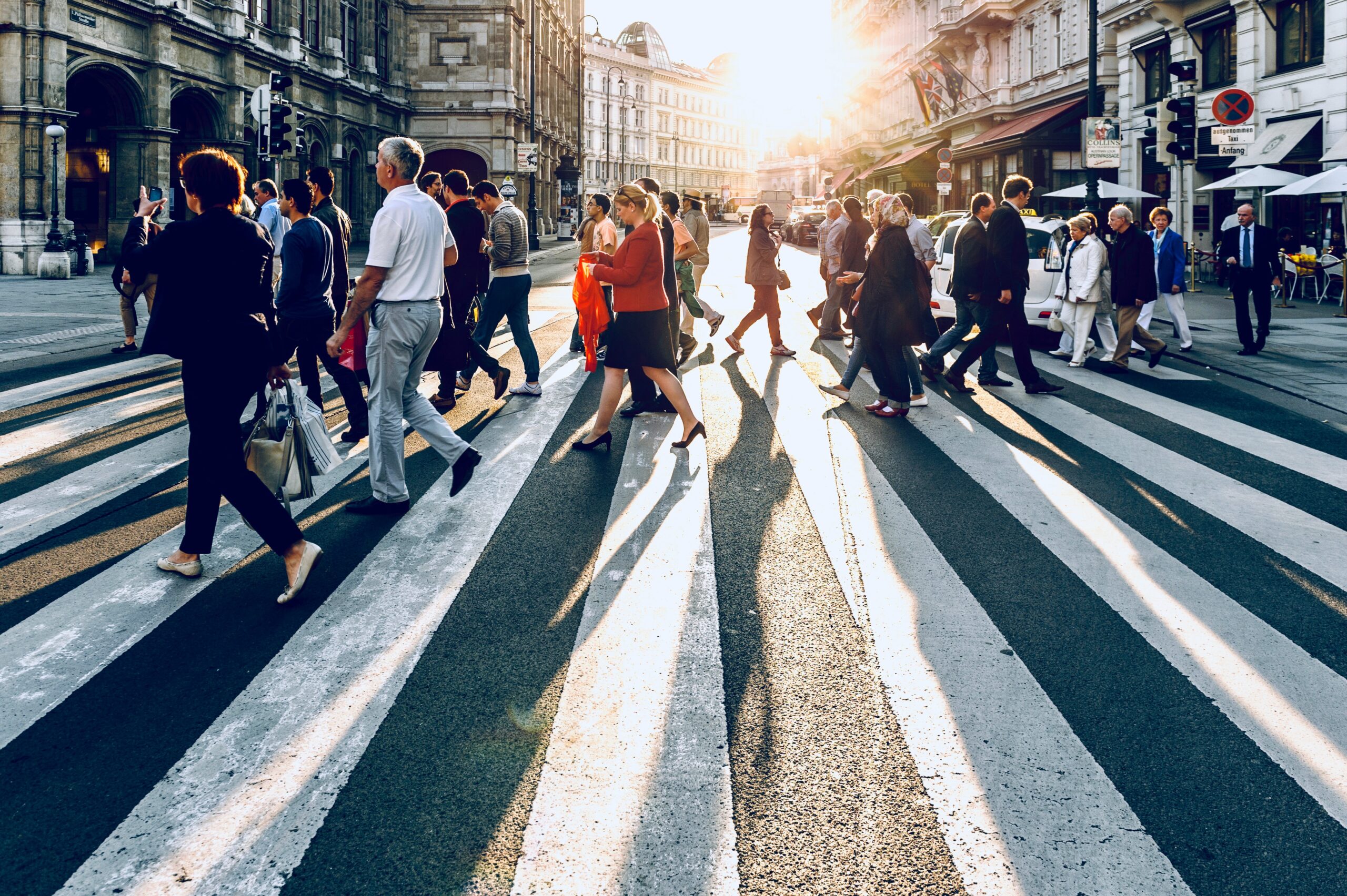 A photo of people crossing a busy city crosswalk.