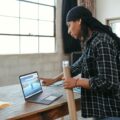 A photo of a woman leaning over a laptop on a desk