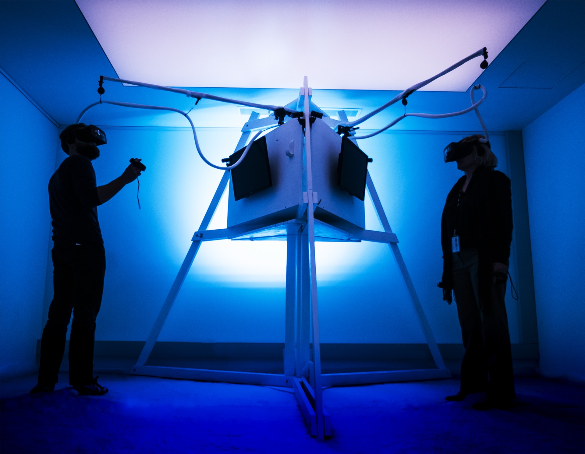 A photo of two people wearing VR headsets against a blue background