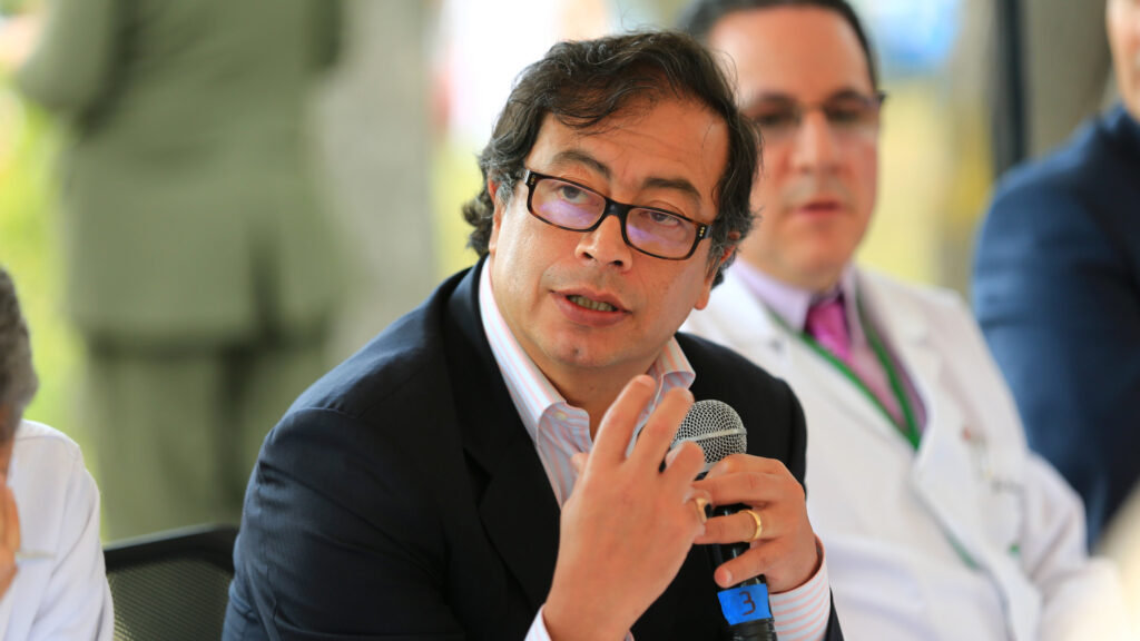 Colombian leader Gustavo Petro speaks into a microphone while sitting on a sunny day