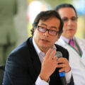 Colombian leader Gustavo Petro speaks into a microphone while sitting on a sunny day