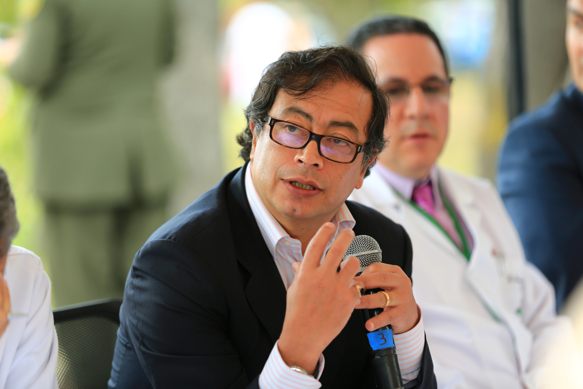 Colombian leader Gustavo Petro speaks into a microphone while sitting on a sunny day