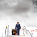 Egypt's President Abdel Fattah al-Sisi, wearing a blue suit and blue tie, exits a plane, standing at the top of a set of stairs that leads onto the tarmac.