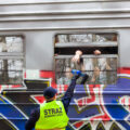 A man in a yellow safety vest hands bottled water to refugees inside a train