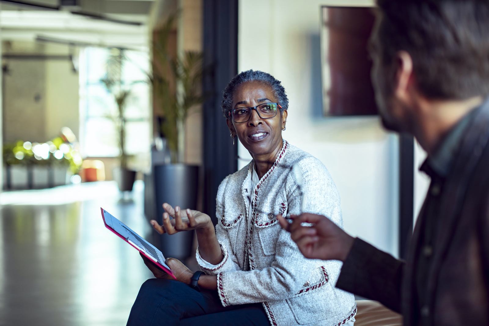 A Black woman in professional dress talks to a white man just out of frame