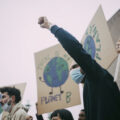 Protestors wearing blue surgical masks hold handmade signs saying There is No Planet B