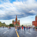 A view of St. Basil's Cathedral in Moscow on a sunny day. People walk in the street next to the cathedral.