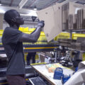 A man in profile pulls down an unassembled cardboard box in a warehouse