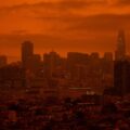 A red haze and smoke from wildfires nearly obscure the city outline of San Francisco.