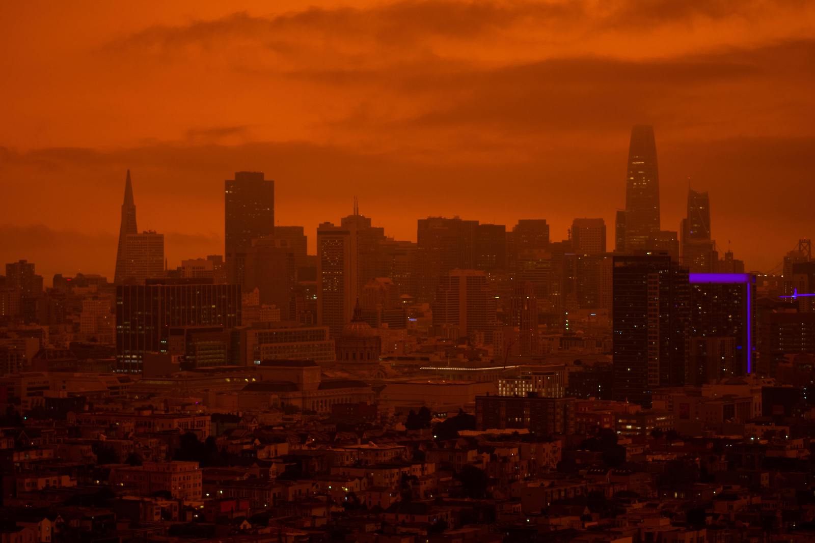 A red haze and smoke from wildfires nearly obscure the city outline of San Francisco.
