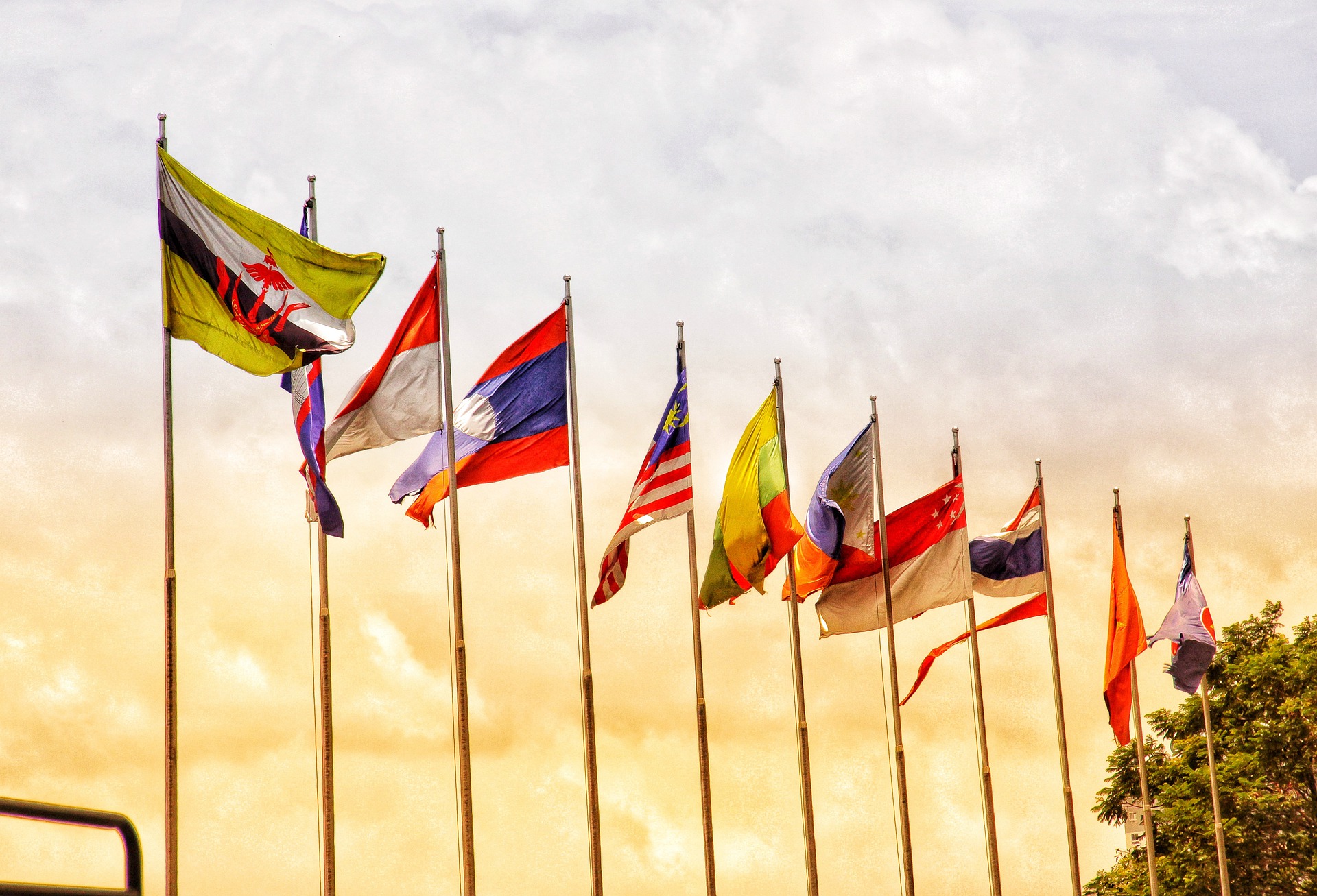 A row of flags against a yellow and blue sky