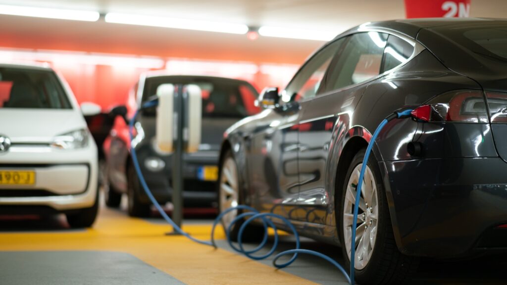 A black electric car is hooked up to a charging port in a garage
