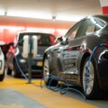 A black electric car is hooked up to a charging port in a garage