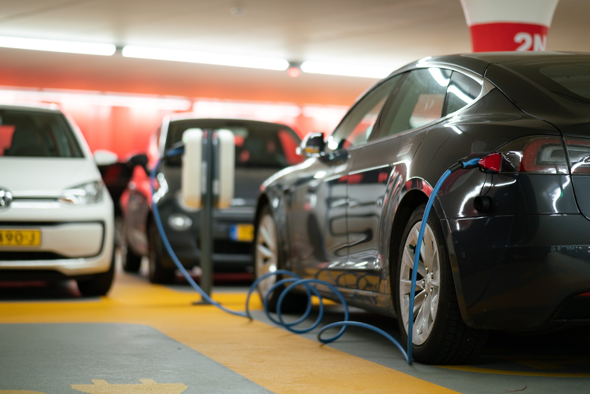 A black electric car is hooked up to a charging port in a garage