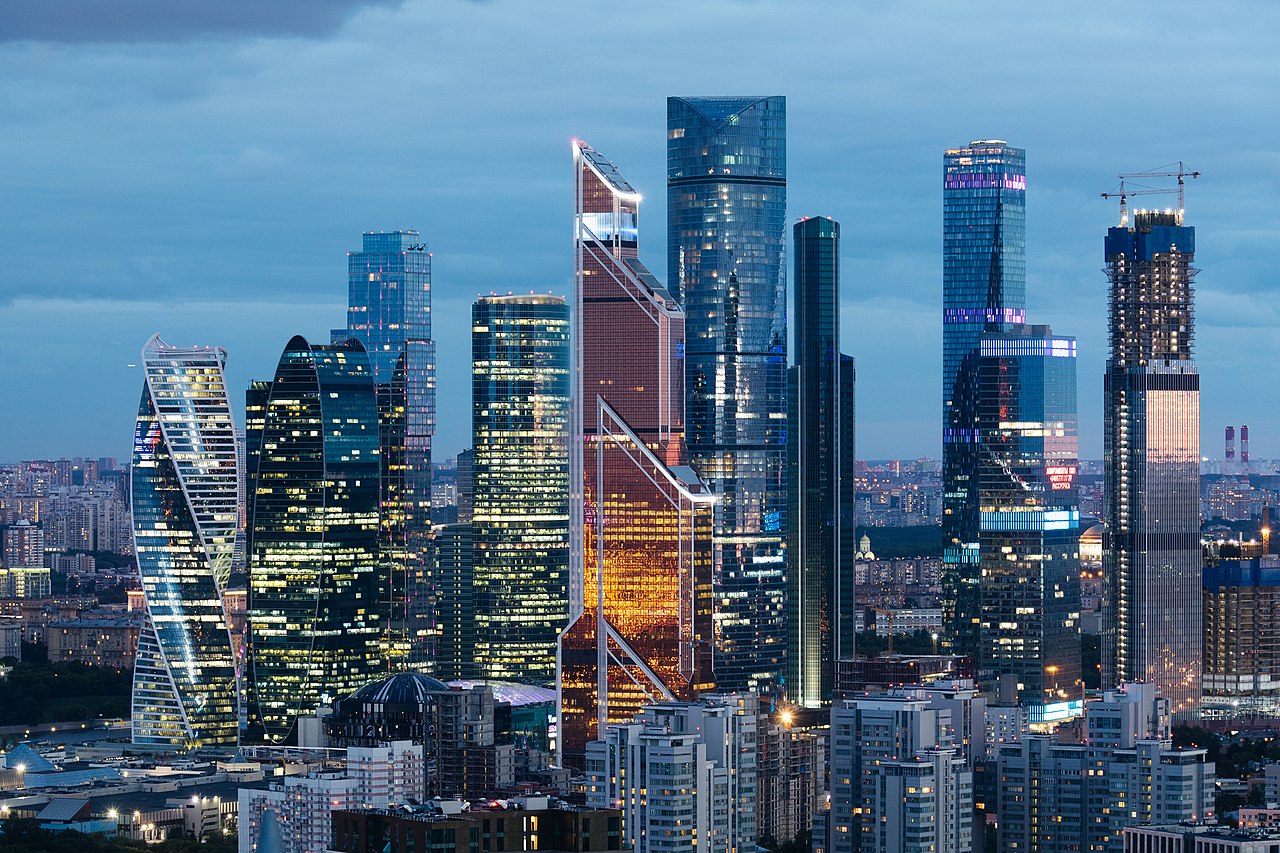 A cityscape with skyscrapers at night, with a large body of water in the background.