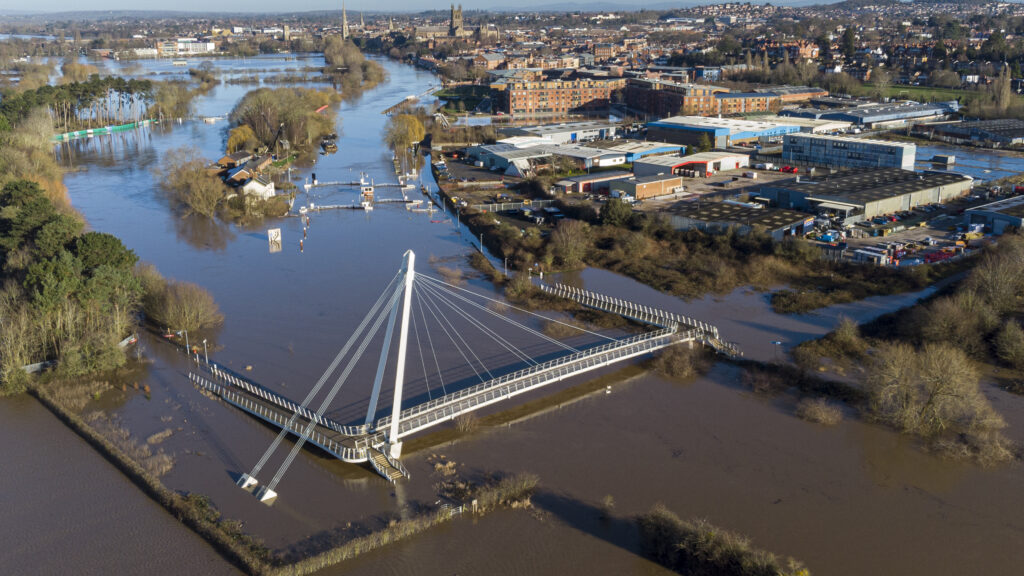 An aerial view of the flood water breaking the banks of the River Severn, showing water and submerged buildings.