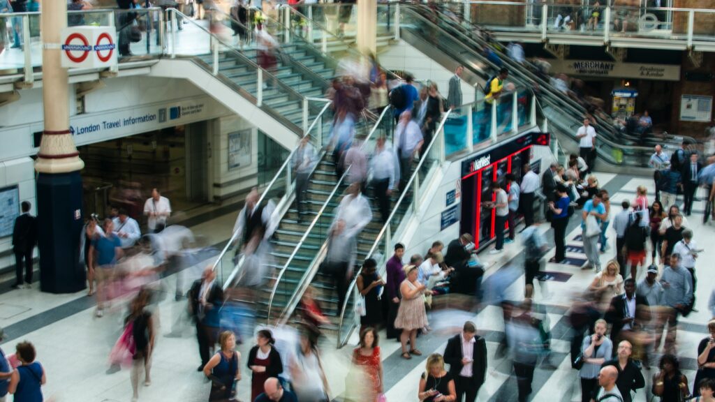 The inside of a British train station, with shops and blurred people moving around