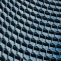 An abstract image of a grey building with a repeating hexagonal pattern.