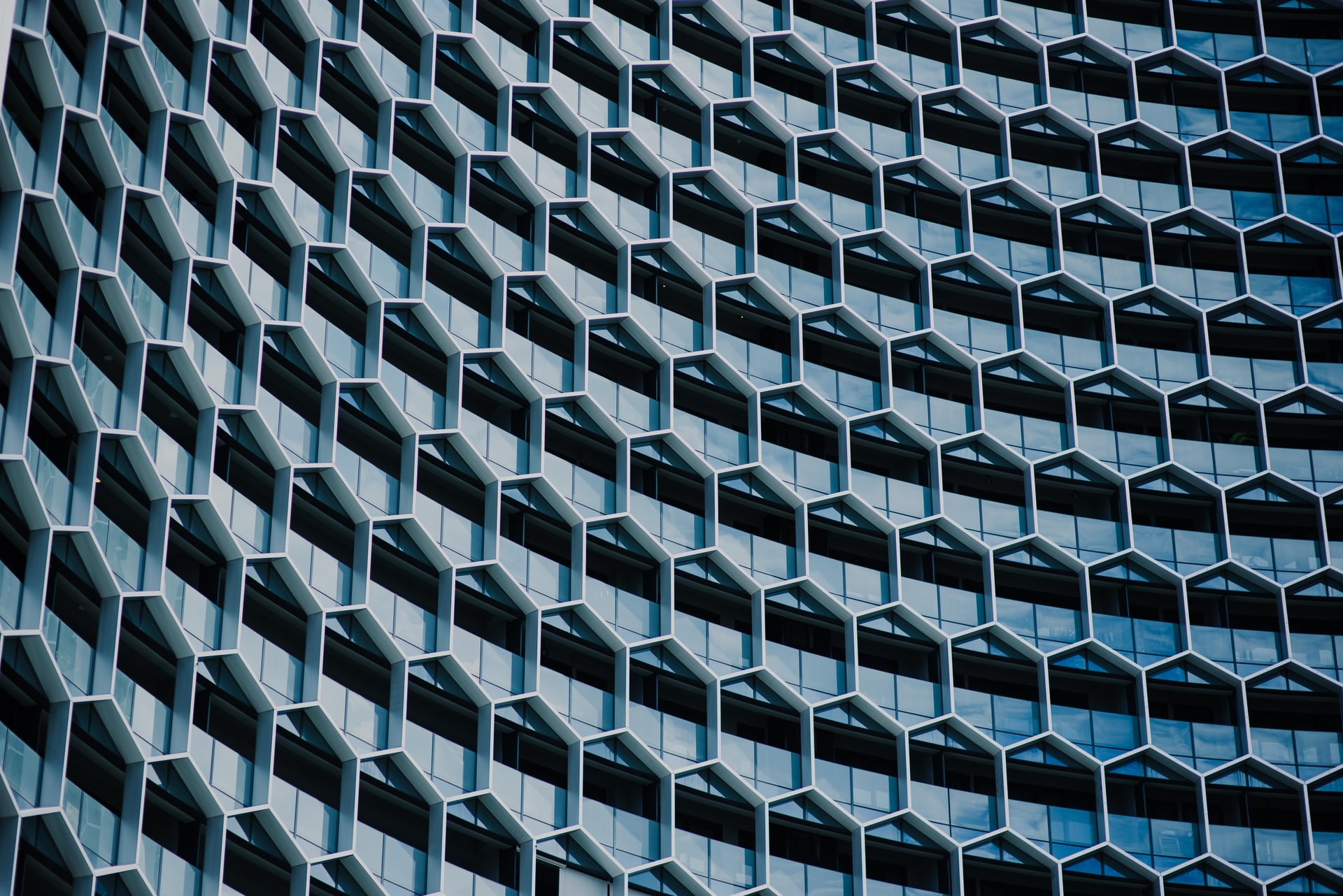 An abstract image of a grey building with a repeating hexagonal pattern.