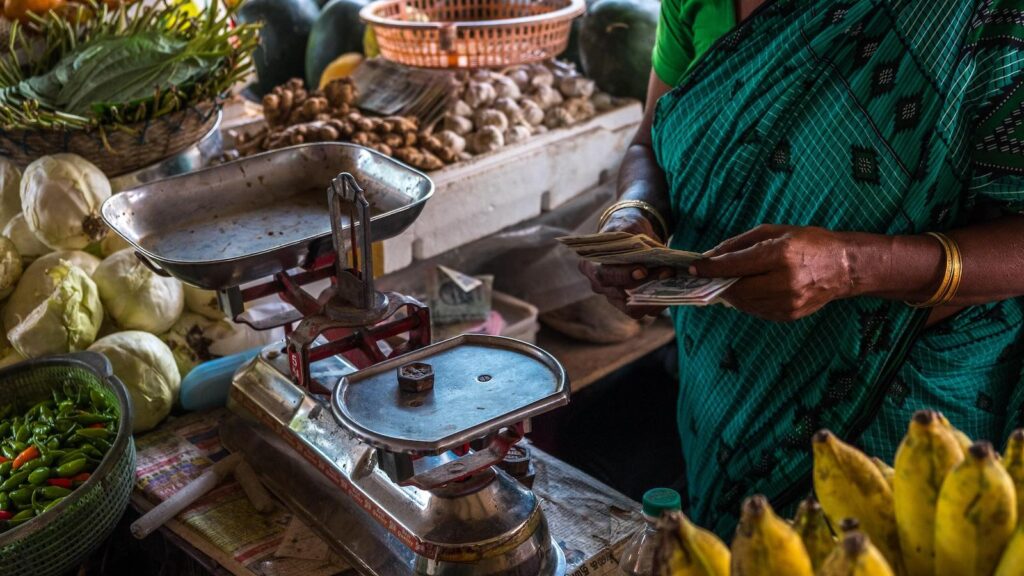 A shopper prepares to pay for produce at a market in India.