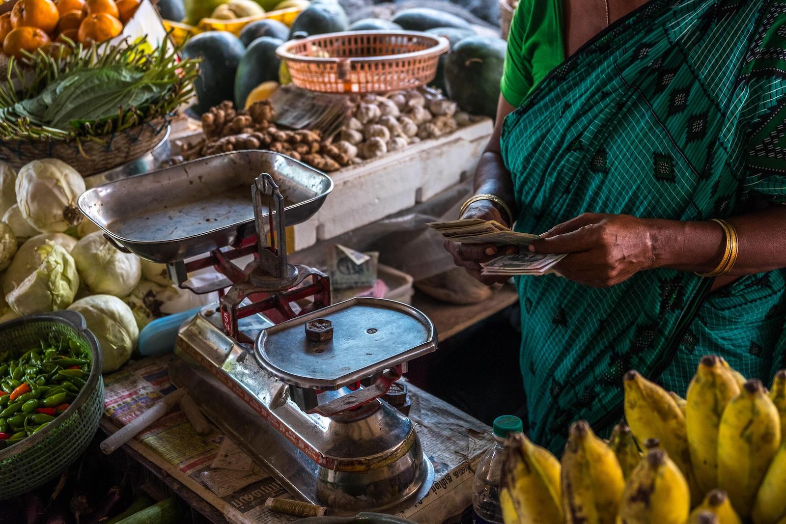 A shopper prepares to pay for produce at a market in India.