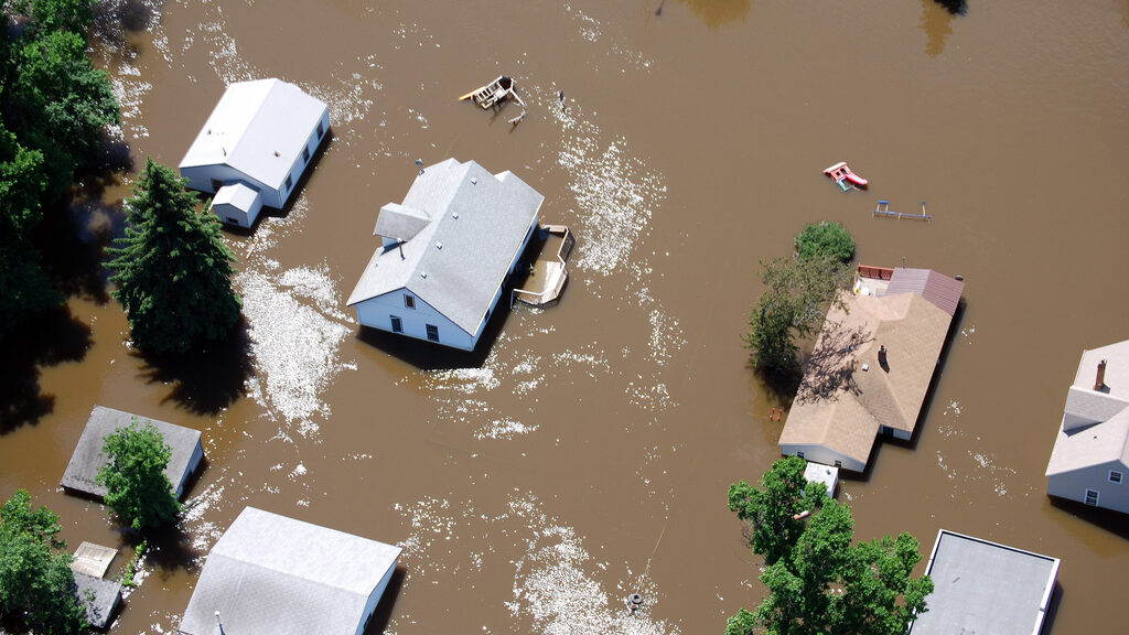 Aerial photo of homes flooded from the Souris River. Roofs can be seen surrounded by muddy water