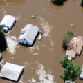 Aerial photo of homes flooded from the Souris River. Roofs can be seen surrounded by muddy water