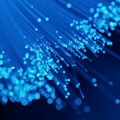 An abstract image of glowing blue fiber optic cables against a dark blue background