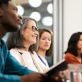 A diverse group of employees sit at a table in lively discussion.