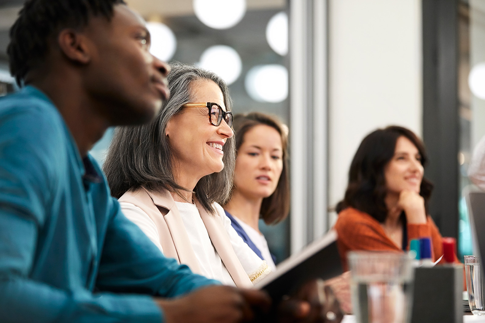 A diverse group of employees sit at a table in lively discussion.