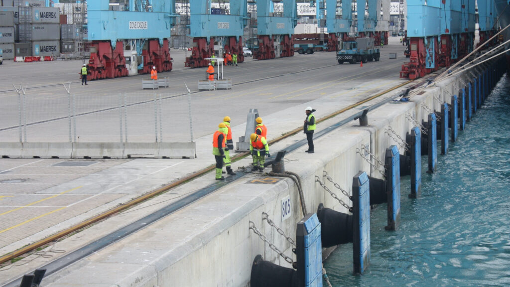 Port staff work at the edge of a dock.