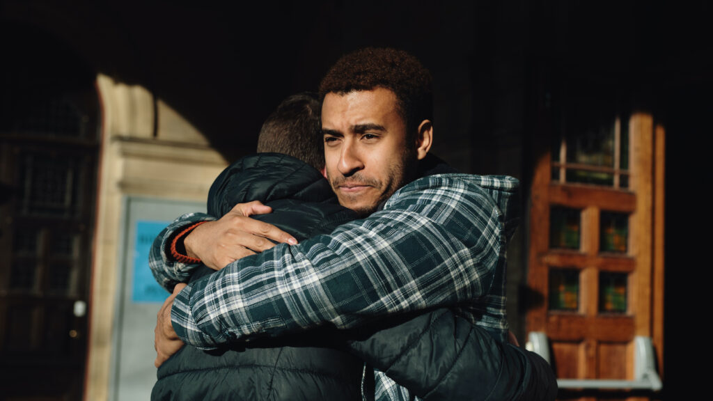 Two men hug outside of a building