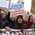 A teenage girl holds a sign that says 