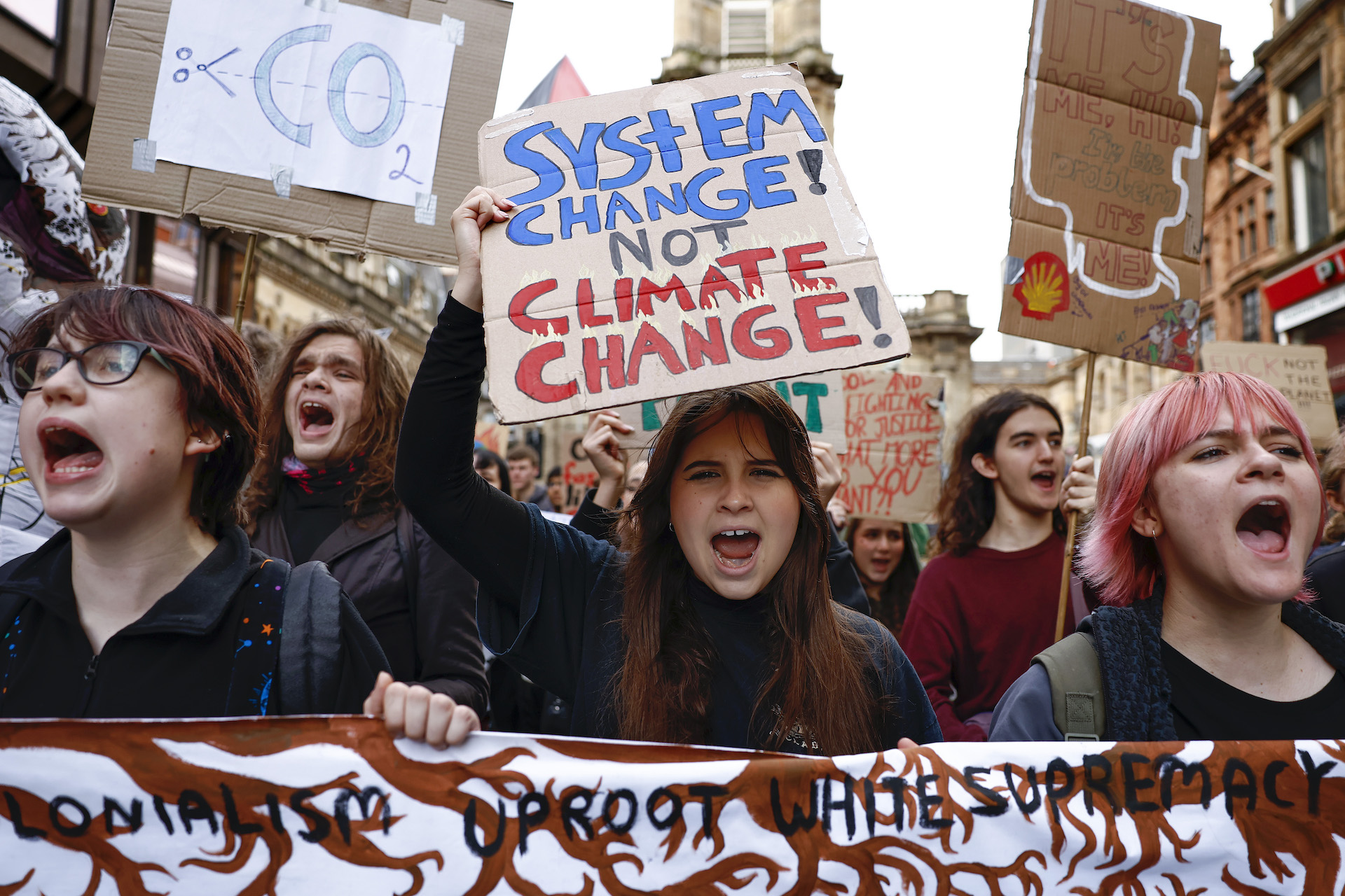 A teenage girl holds a sign that says