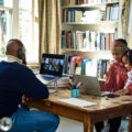 Two black parents with their young child working in home office